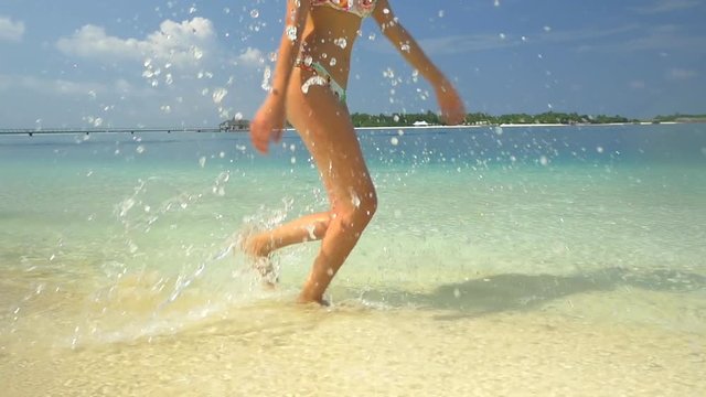 SLOW MOTION: Young woman running in surf at sandy beach