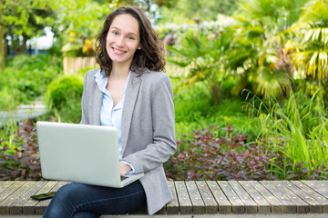 Young attractive business woman working at the park during a pau