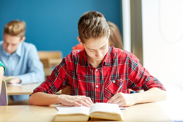 group of students with books writing school test