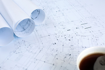 A cup of coffee and architectural blueprints on working table