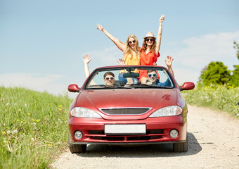 happy friends driving in cabriolet car at country