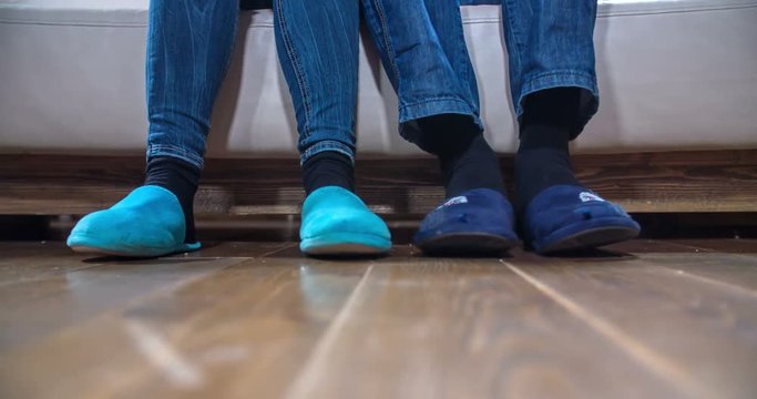 Young couple is having cute light blue and dark blue slippers on and they are tapping with their feet first each in their own rhythm and then together. Close-up shot.
