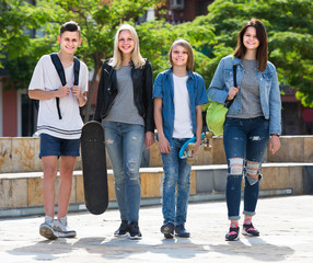 Portrait of four teenagers walking together in town on summer da