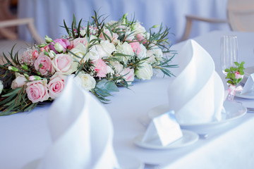 Table set for an event party or wedding reception. Large floral arrangement of roses and peonies