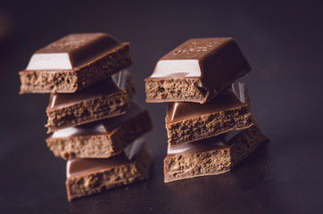 Two chocolate buildings on a dark background. energy and sugar. Broken bar. Chocolate blocks stack 