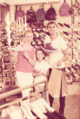 Family choosing shoes in sport shop.