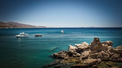 Tourist boats on the sea. Sea landscape with boats on the sea in Crete island Greece. There are a rocks formation in the foreground.