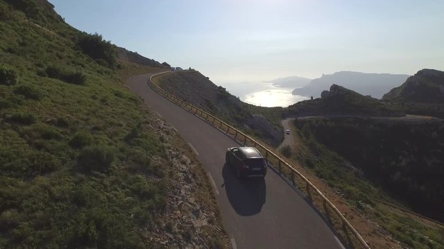 AERIAL: Car driving up the mountain pass above the ocean