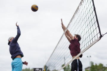 Blurred volleyball players jump to attack and block.