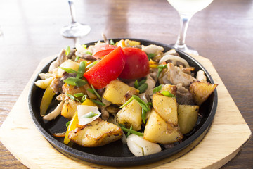 fried potatoes with meat and tomatoes in a cast iron skillet