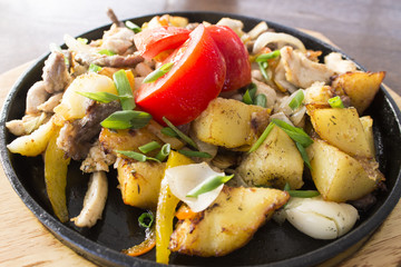 fried potatoes with meat and tomatoes in a cast iron skillet