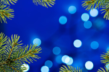 Fototapeta na wymiar Blue Christmas Background with Christmas Twig and Unfocused Ligh