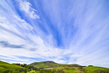 Landscape scenery of green valley, hill and cloudy blue sky