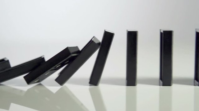Row of dominoes with one falling over
