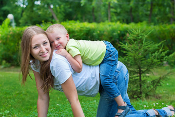 Cheerful Smiling Mother and Boy playing on her Back