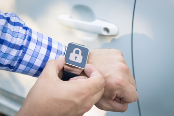 Close up shoot of male hands locking the car doors by using smart watch remote control security app.