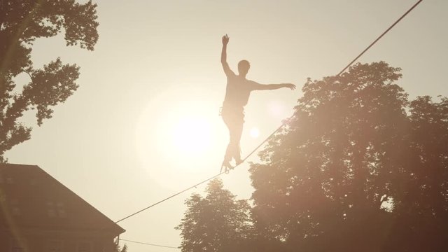 Man balancing on slackline between the houses in big city