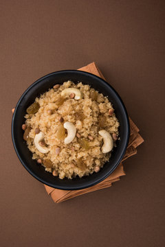 indian gujrati or maharahashtrian or south indian sweet dish lapsi broken wheat sweet pudding payasam pongal or daliya sheera, famous sweet food in india, also known as halwa, served in red bowl