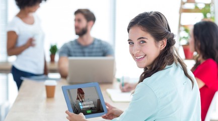 Composite image of smiling businesswoman using tablet 
