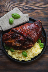 Baked crispy pork knuckle served with mashed potato, close-up