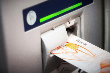 Hand inserting ATM card into bank machine to withdraw money
