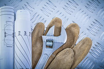 Safety gloves rolled engineering drawings pipe wrench on grooved