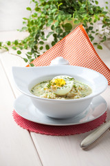 Sorrel soup with egg in white bowl.
