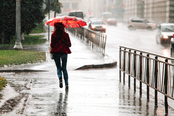 Woman runs with umbrella when heavy rain drops