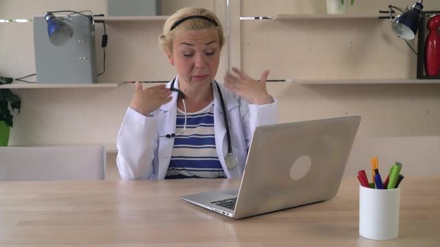 Doctor fanning herself with her hand. Middle aged woman working in office where don't works air conditioning. She feels the heat attack at the working place. Happy caucasian physician wearing in white