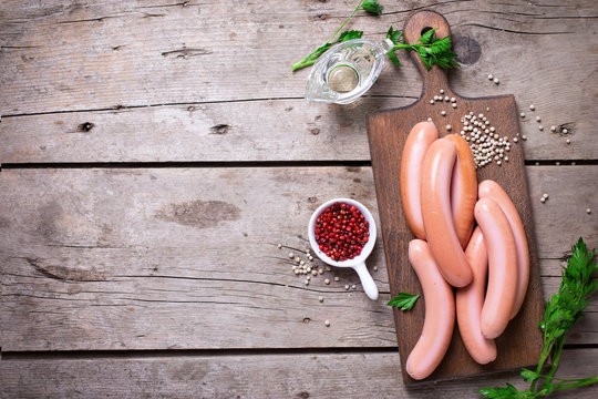 Sausages on board  with herb and spices on vintage wooden background. Selective focus. Flat lay with copy space.