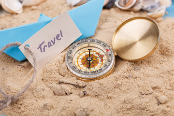 Fototapeta na wymiar compass in the sand with sign travel
