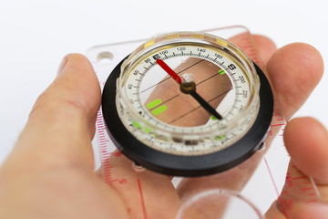 Detail of hand holding glass compass on white background