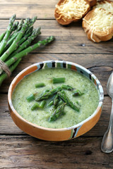zuppa vellutata di asparagi sfondo tavolo legno rustico