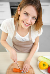 Beautiful girl cutting vegetables in kitchen