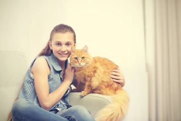 Beautiful girl with cute cat on grey couch
