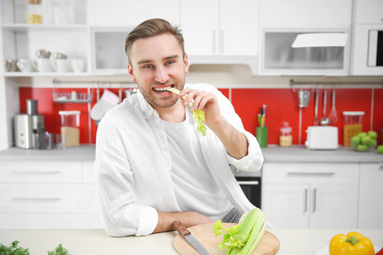 Handsome Man Eating Celery In Kitchen