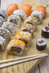 Different Sushi rolls,wasabi and ginger on a plate on wooden bac