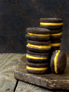 Chocolate Sandwich Cookies With Orange Cream Piled High Back On A Dark Background