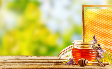 Jar of fresh honey with flowers and honeycomb