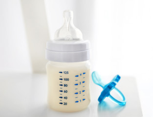 Baby milk bottle and pacifier on white background