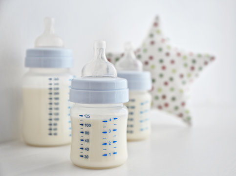 Baby milk bottles and toys on white background