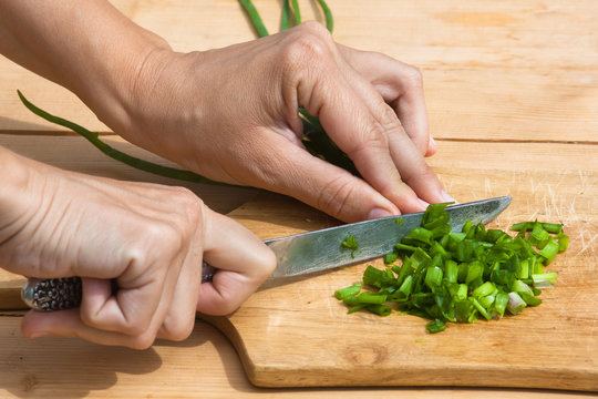 hands chopping green onion on the cutting board