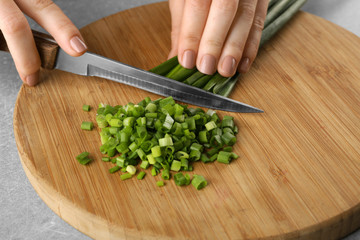Female hands cutting onion on wooden board