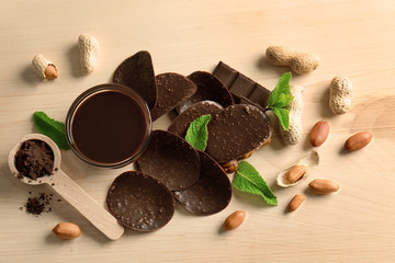 Composition of chocolate chips and spoon with cocoa powder on wooden background