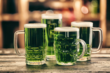 Different glasses of green beer on wooden table