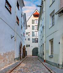 Narrow street in old Riga city, Latvia. Walking through medieval streets of old Riga tourists can feel unforgettable atmosphere of the Middle Ages

