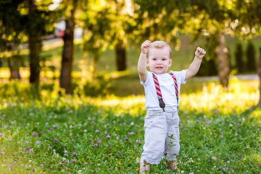 Cute Toddler Boy Sitting On The Ground In Spring Garden