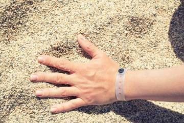 Female hand with resort bracelet on the sand