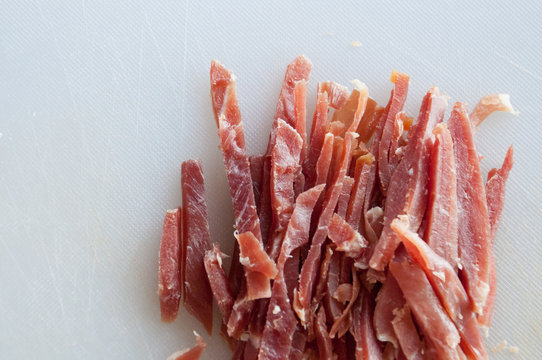Cut cured ham on white cutting board
