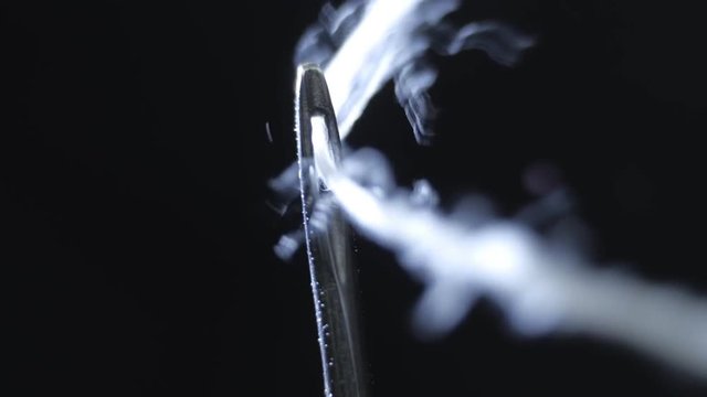 Successfully threading white thread in the eye of a needle. Macro